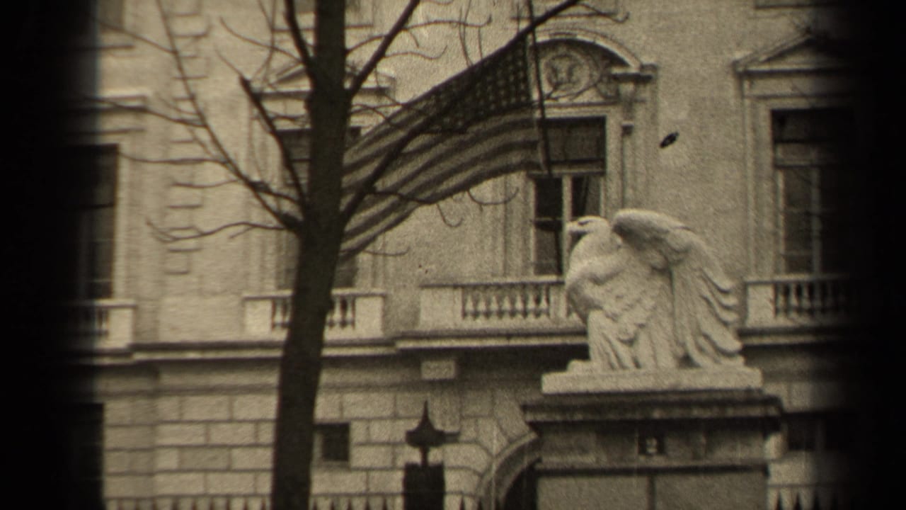 1947 Paris 8mm frame showing a stone facade, American flag, eagle statue, bare tree branches, and a dark vertical film edge.