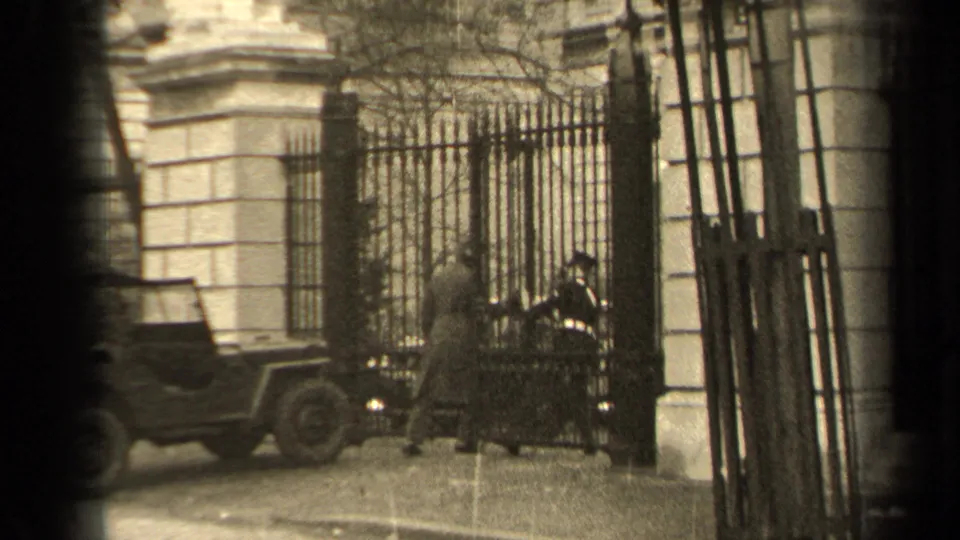 The uniformed guard appears to let the visitor through the iron gate outside a Paris building in 1947.