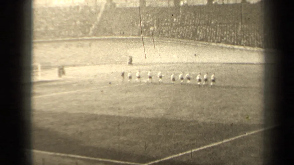 1947 Paris football players appear lined up on the field, filmed from a distant spectator viewpoint in a crowded stadium.