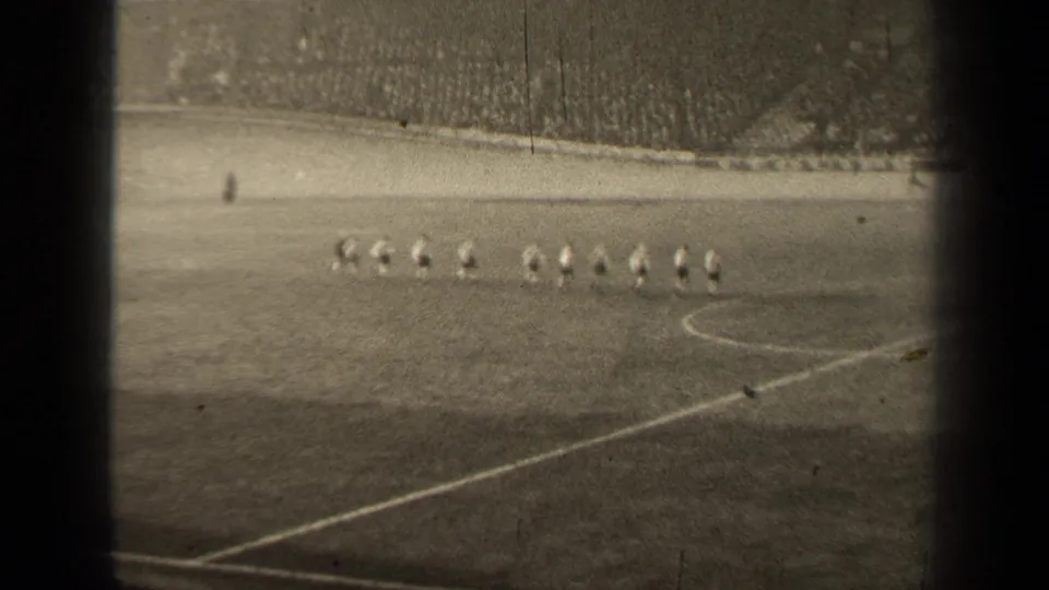 Spectator-shot 8mm view of a 1947 Paris football lineup, with players small against the field and stadium crowd.