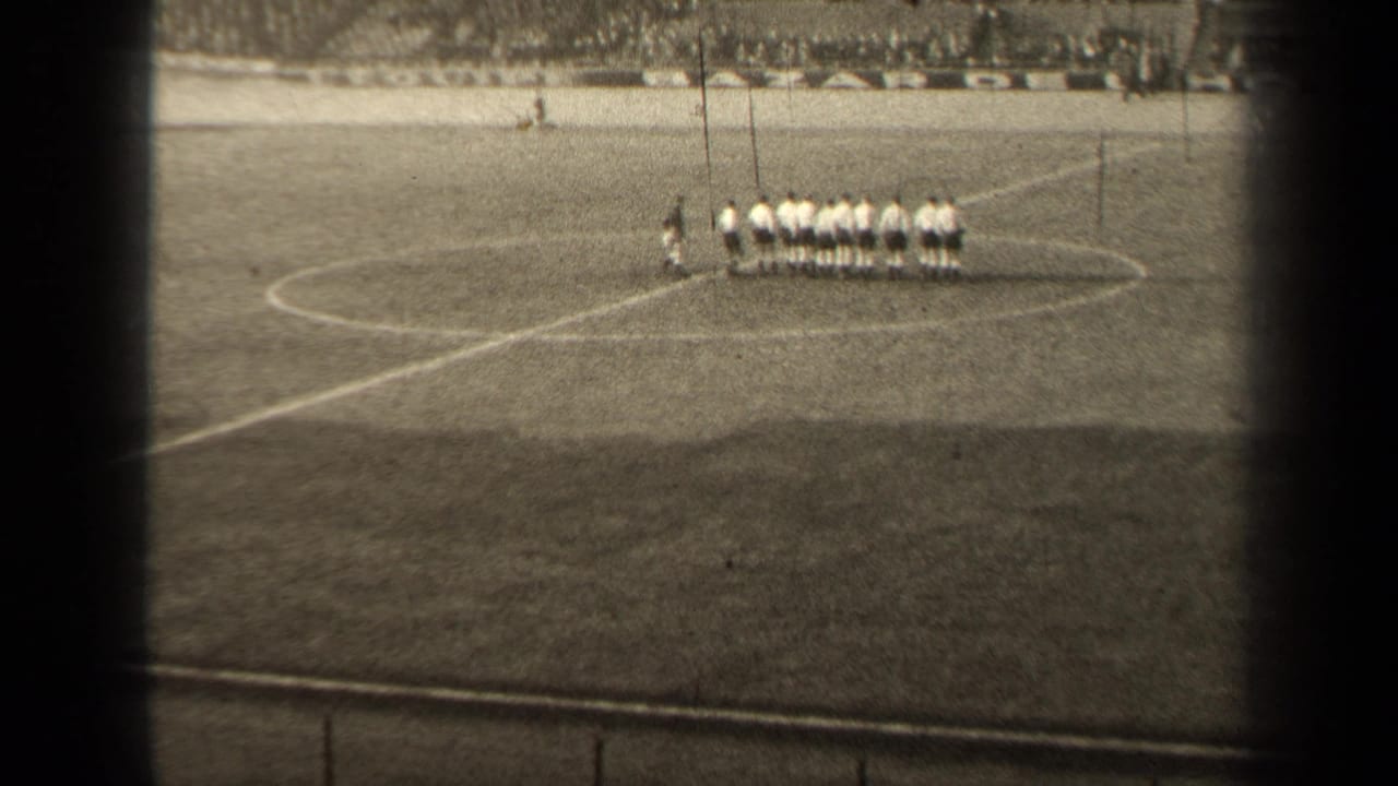 1947 Paris soccer players appear lined up near midfield, seen from a distant spectator viewpoint in black-and-white 8mm footage.
