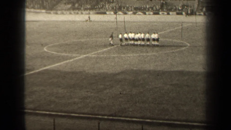 1947 Paris soccer players appear lined up near midfield, seen from a distant spectator viewpoint in black-and-white 8mm footage.
