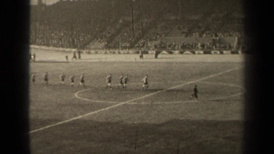 1947 Paris 8mm frame with teams jogging near midfield in a large stadium, viewed from a distant spectator position.