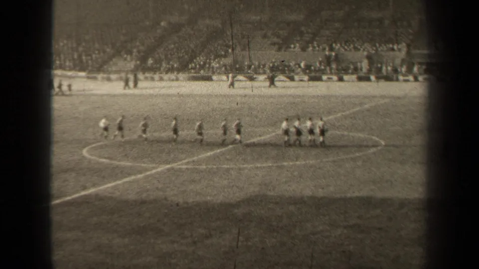 1947 Paris 8mm frame showing players grouped near the center circle, with stadium seating and spectators in the background.