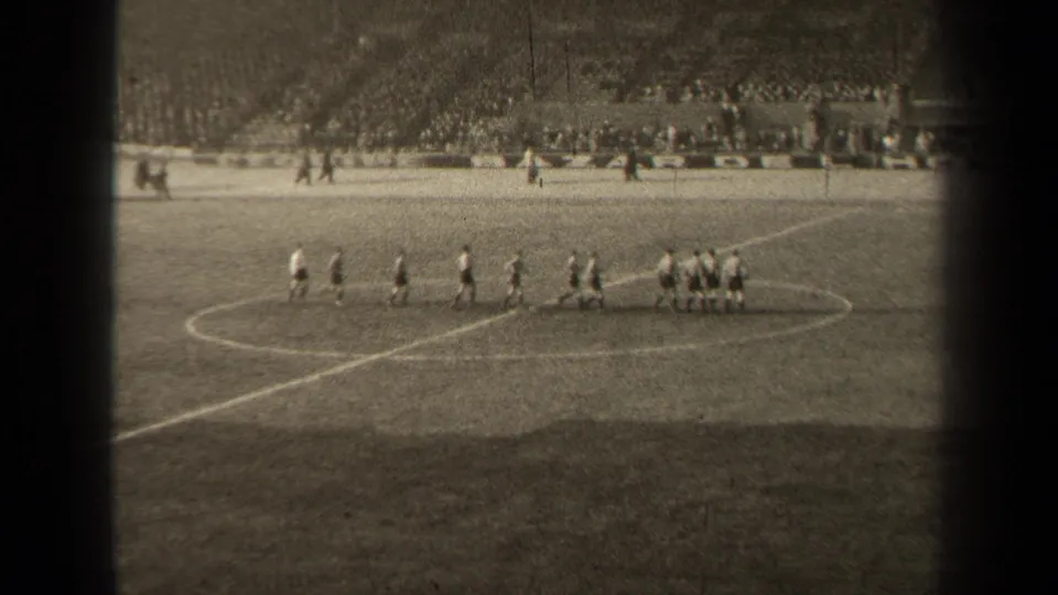 1947 Paris soccer footage showing two groups of players near midfield with a stadium crowd beyond the grass pitch.