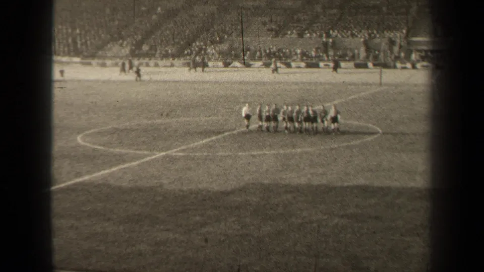 A distant 1947 Paris stadium view shows soccer players gathered near the center circle as spectators watch from the far side.