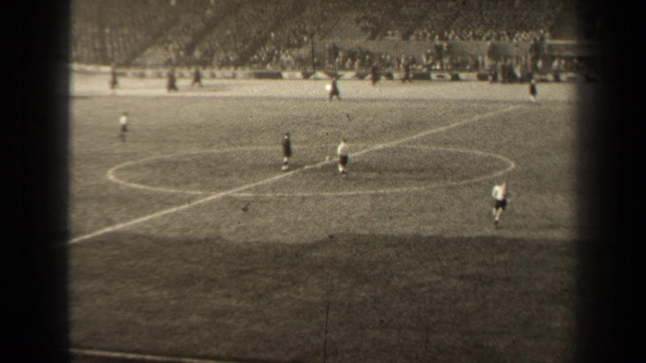 Wide 8mm stadium view in Paris, France, showing football players spread around the center circle during a 1947 match.