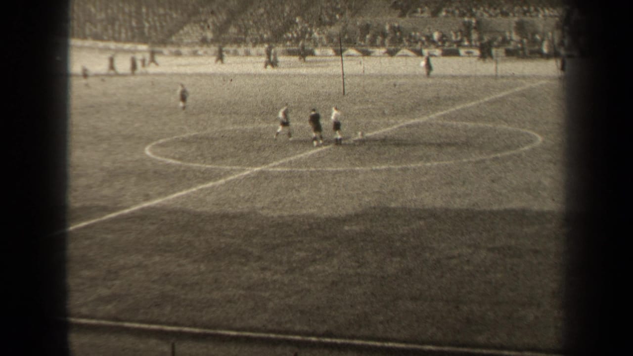 1947 Paris soccer play seen from the stands, with players near midfield and a crowded stadium terrace beyond the marked grass field.