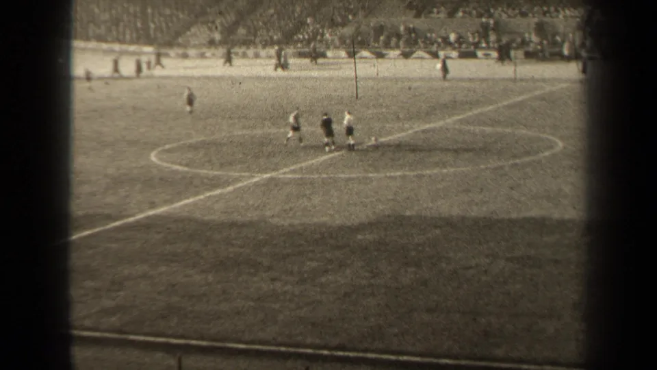 1947 Paris soccer play seen from the stands, with players near midfield and a crowded stadium terrace beyond the marked grass field.