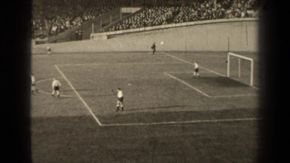 Late in the short 1947 Paris soccer clip, players remain near the penalty area while the goal and packed stadium seating frame the scene.