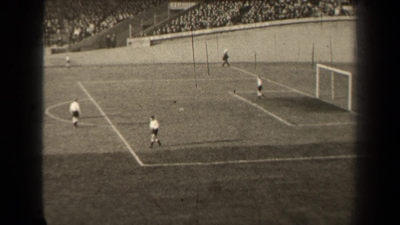 1947 Paris 8mm frame showing distant field hockey players in white uniforms near a goal, viewed from the stands.