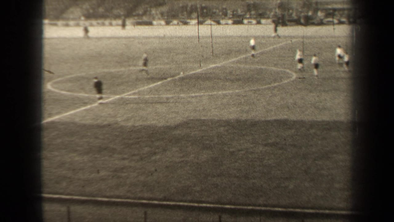 Distant 1947 Paris soccer play near the center circle, framed by dark vertical bands and a soft 8mm home-movie look.