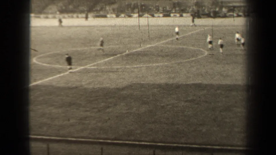 Distant 1947 Paris soccer play near the center circle, framed by dark vertical bands and a soft 8mm home-movie look.