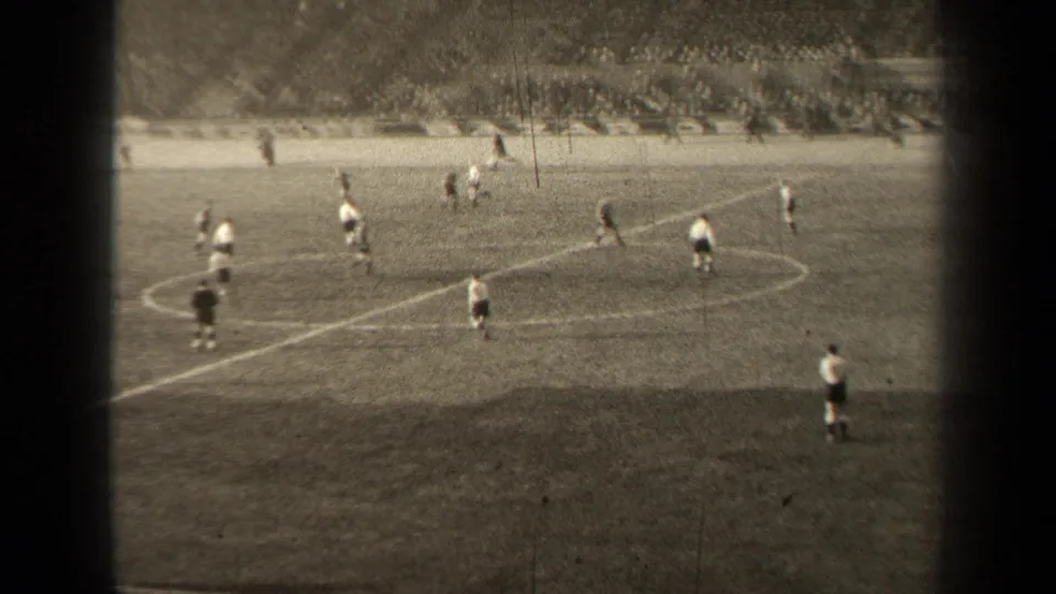 Players in light and dark kits move around midfield during the 1947 Paris football match, seen from a distant stand position.