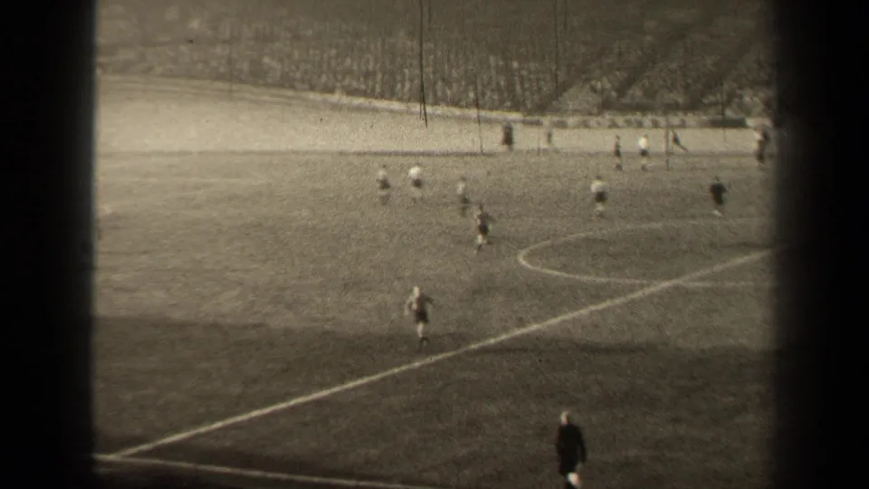 Wide spectator view of the Paris soccer match, showing field markings, distant players, and a packed stand beyond the far side.
