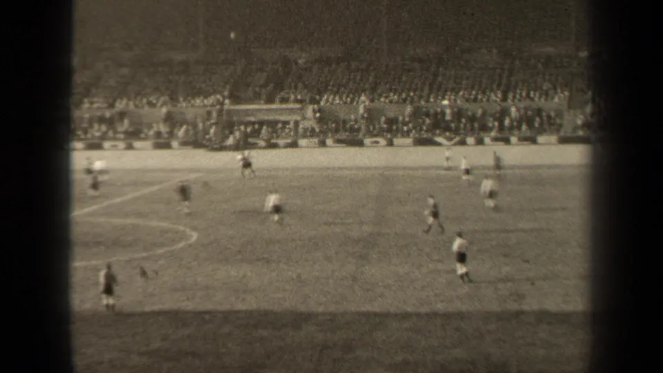 Paris soccer action in 1947 seen from a distant home-movie viewpoint, with players on the pitch and a large crowd in the background.