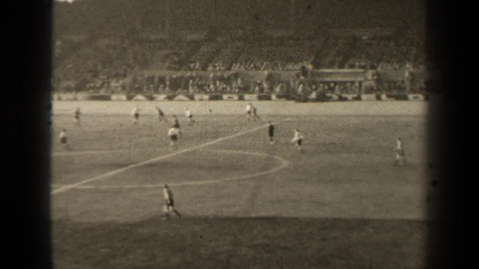 1947 Paris home-movie view of a soccer match, with players crossing a marked field before crowded stadium terraces.