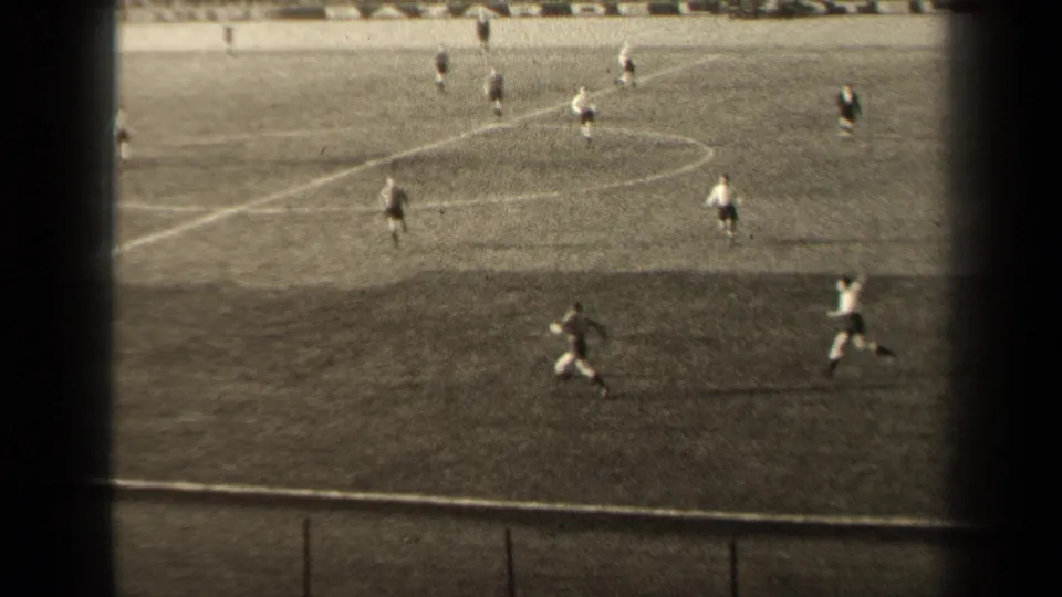 1947 Paris stadium soccer view from the stands, with players running near midfield, pitch markings and a low barrier in the foreground.