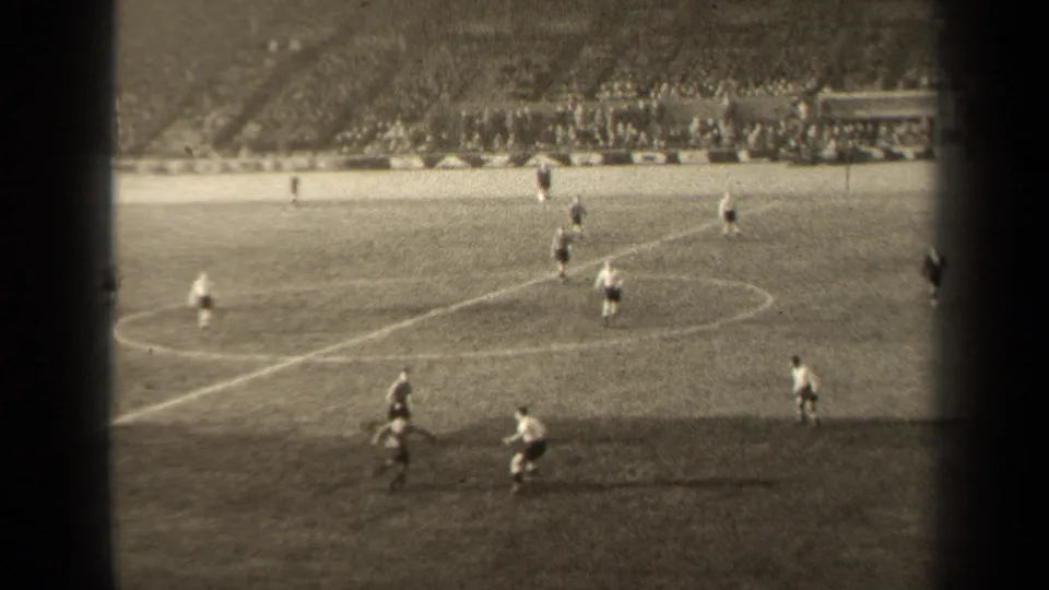 1947 Paris soccer match seen from the stands, with players moving near midfield and a crowd visible across the stadium.