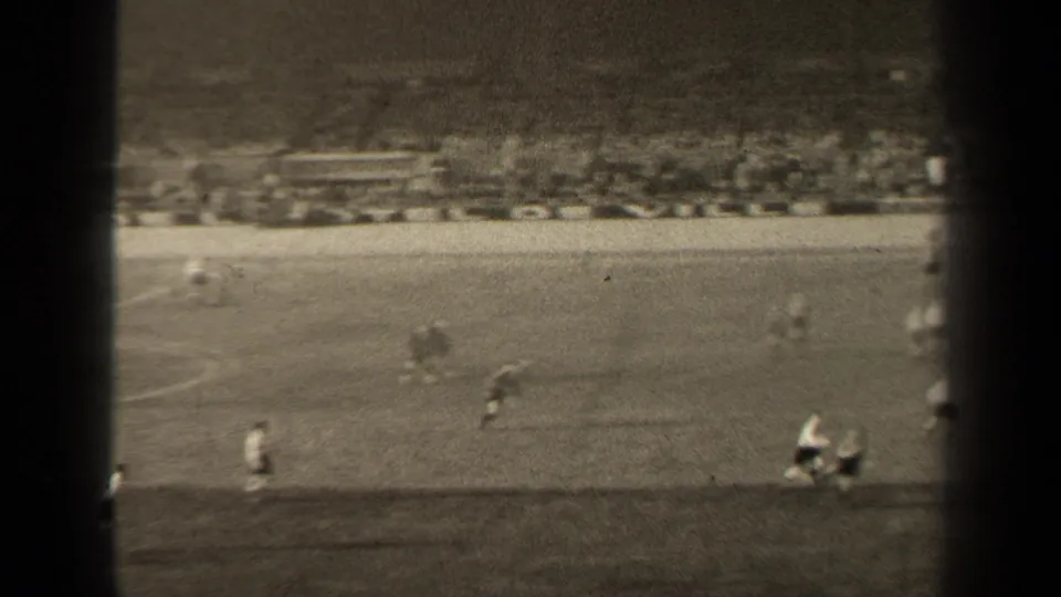 Wide 8mm view of the 1947 Paris match, showing players in motion on the pitch with blurred stadium seating in the background.