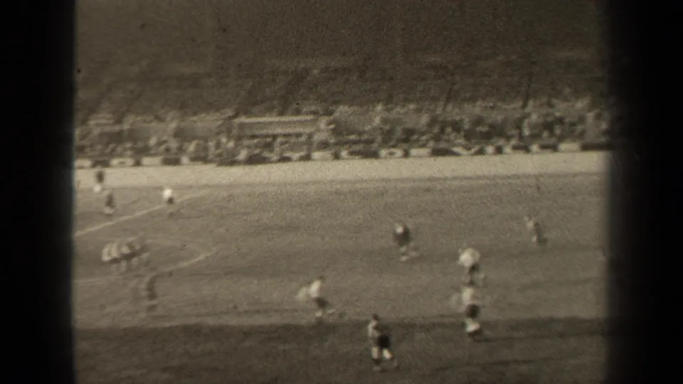 Wide 1947 Paris stadium view showing players advancing on the grass pitch while spectators watch from the far stands.
