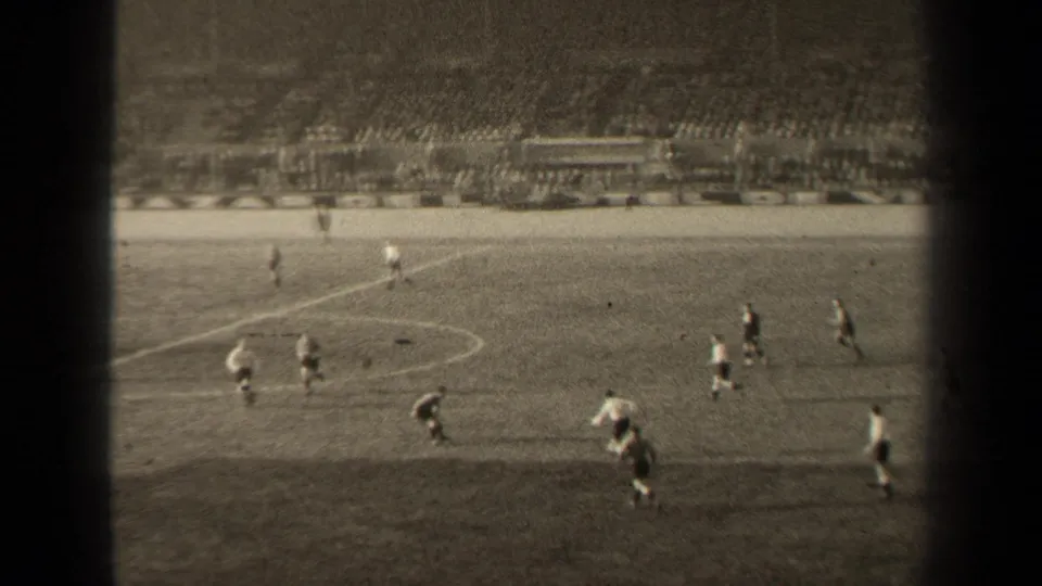 1947 Paris football match seen from the stands, with players moving near midfield and a large seated crowd beyond the pitch.