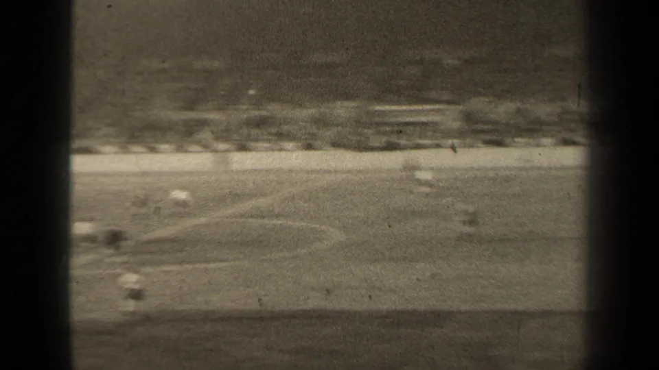 High-angle black-and-white view of a 1947 Paris soccer match, with players blurred in motion across the pitch.