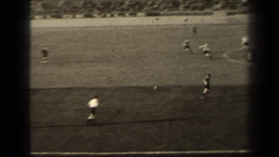 1947 Paris soccer footage shows players on a grass pitch, with dark film borders and stadium seating beyond.