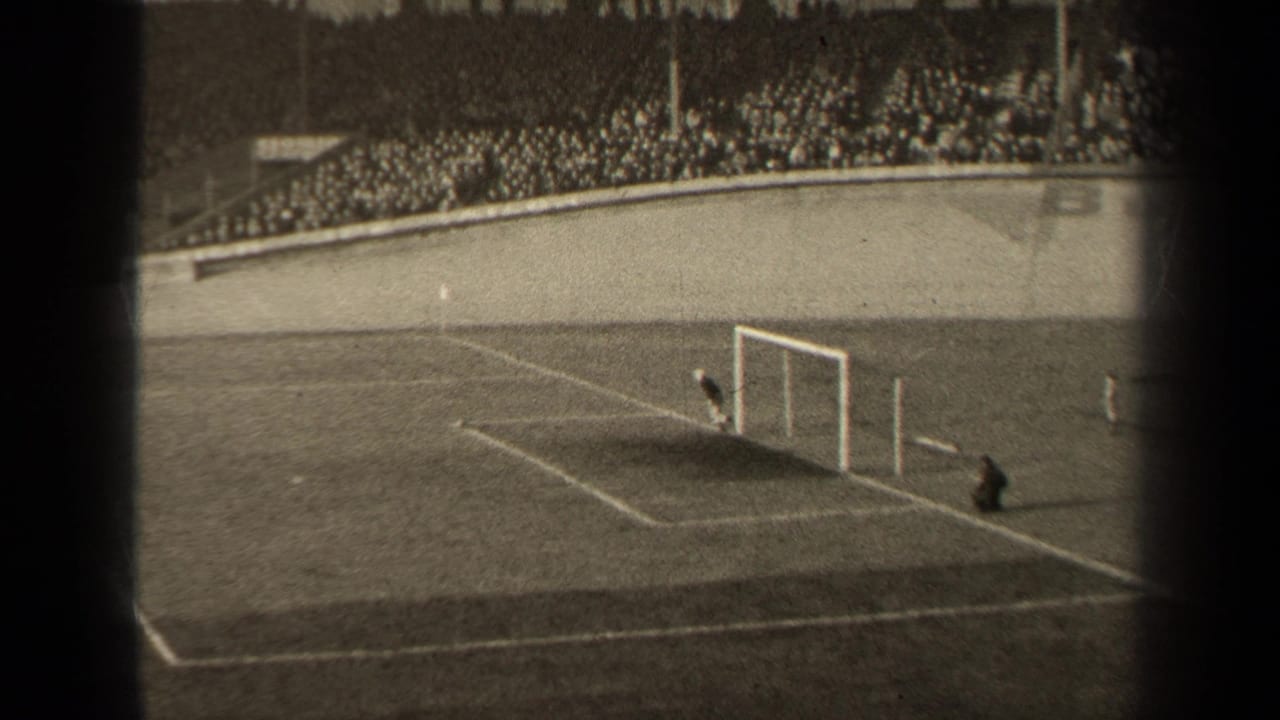 1947 Paris 8mm frame showing the soccer goal area, a goalkeeper near the net, field markings, and a packed stadium crowd in the background.
