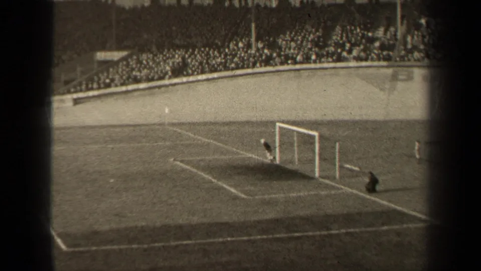 1947 Paris 8mm frame showing the soccer goal area, a goalkeeper near the net, field markings, and a packed stadium crowd in the background.