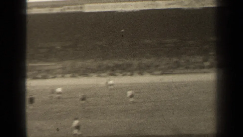 Soft, motion-blurred 1947 Paris 8mm frame showing soccer players moving across the field with the ball near the lower portion of the shot.