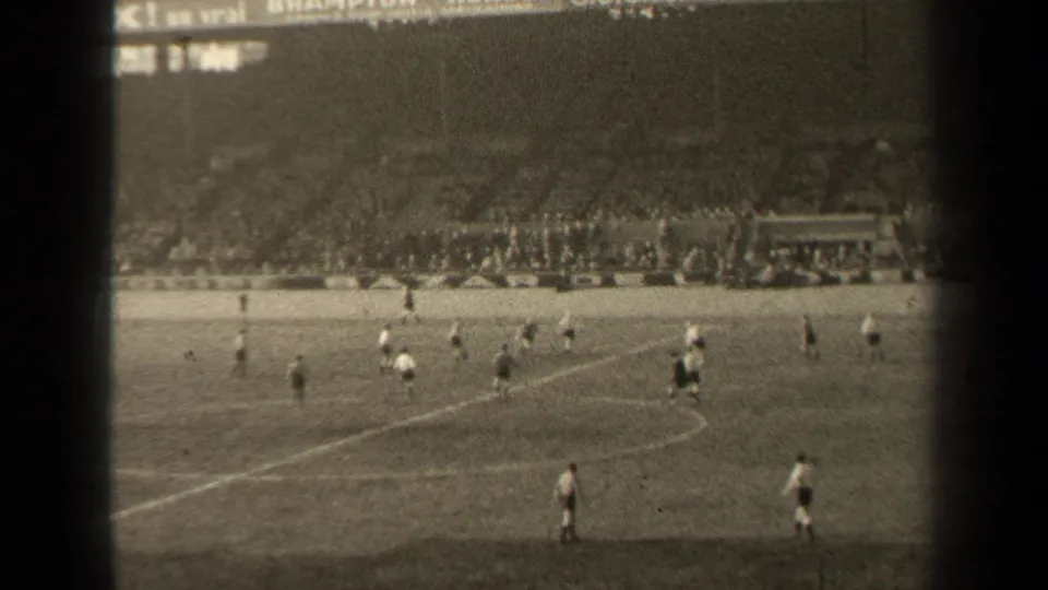 1947 Paris 8mm frame showing a football match from spectator distance, with players on the pitch and a packed stadium crowd beyond.