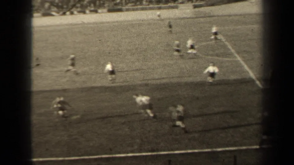 1947 Paris 8mm frame with a closer, slightly blurred view of football players moving near the sideline during active play.