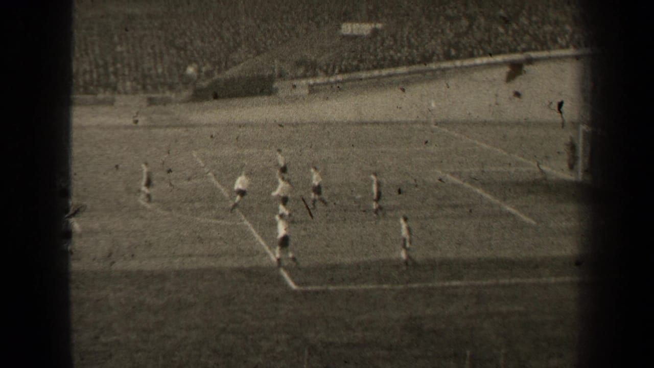 1947 Paris soccer match footage showing players in light and dark uniforms moving near the penalty area before packed stadium seating.