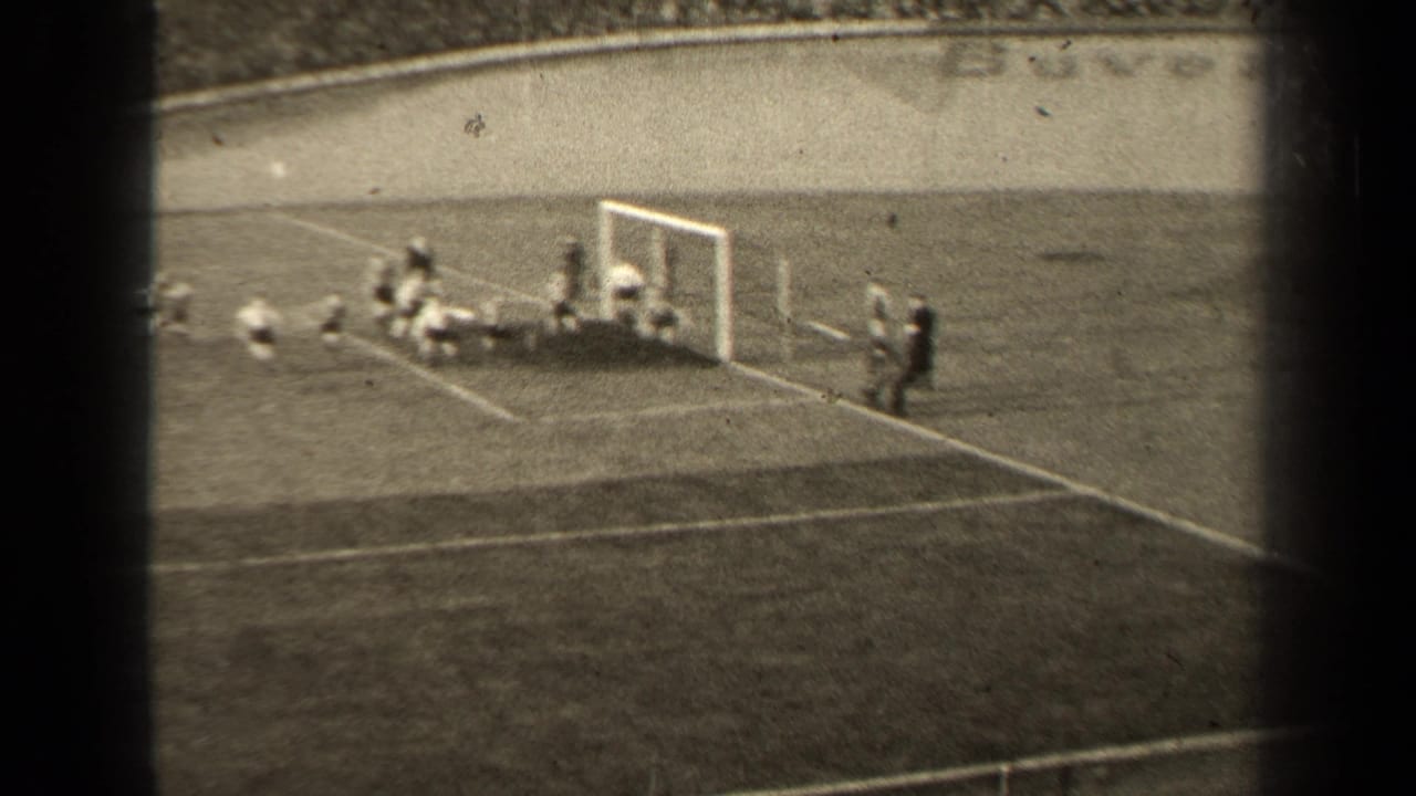 Several soccer players cluster around the goalmouth as the goalkeeper area fills with movement.