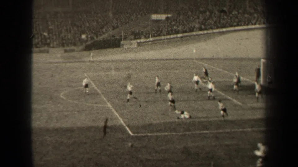 1947 Paris soccer match frame showing open play near the penalty area, with players running and spectators in the stands.