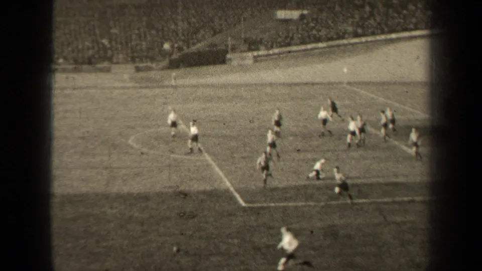 1947 Paris soccer match view from the stands, with players in light shirts and dark shorts moving near the penalty area.