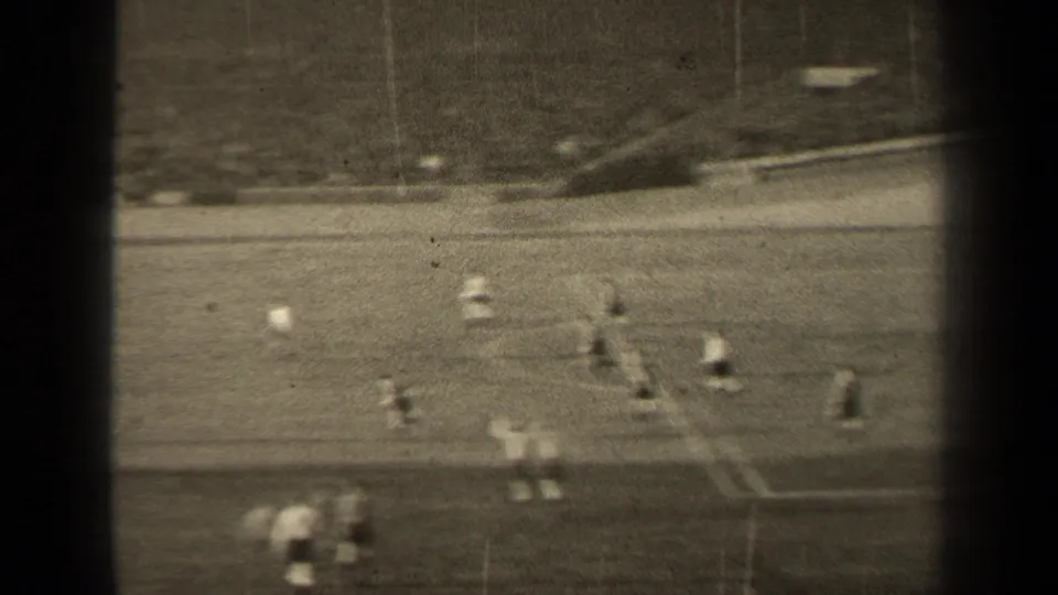 A softer 8mm frame from the 1947 Paris match shows players spread across the pitch with the stands and crowd visible beyond.