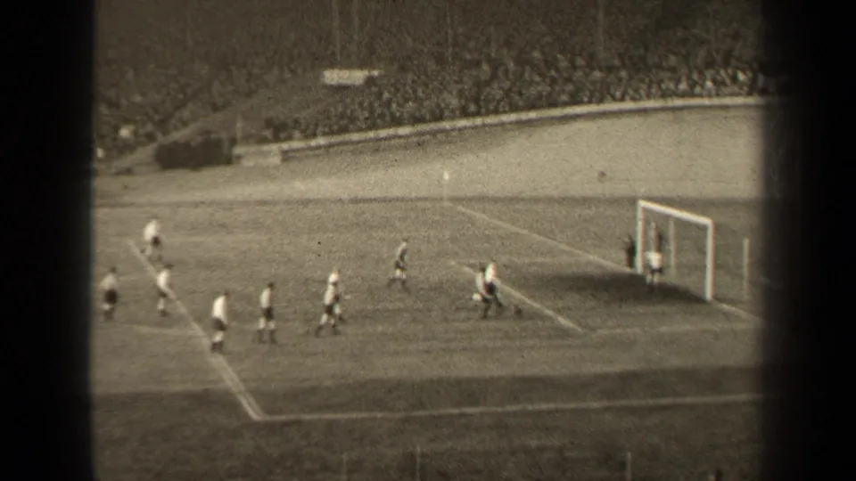 1947 Paris soccer match frame showing the goal area, scattered players, field markings, and a large stadium crowd in the background.