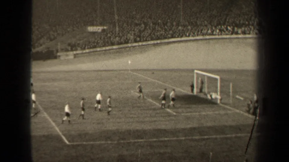 1947 Paris football match seen from the stands, with players near the goalmouth and a large stadium crowd behind them.