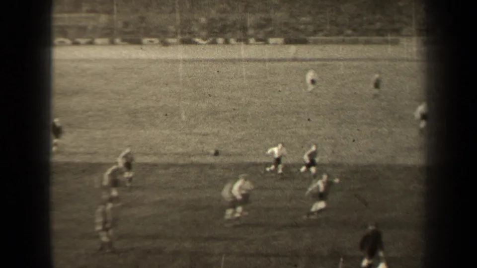 Sideline action in the 1947 Paris football match, filmed from a high spectator angle with soft 8mm focus.