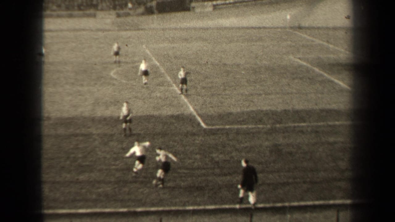 Soccer players contest the ball near the sideline on a marked grass field.