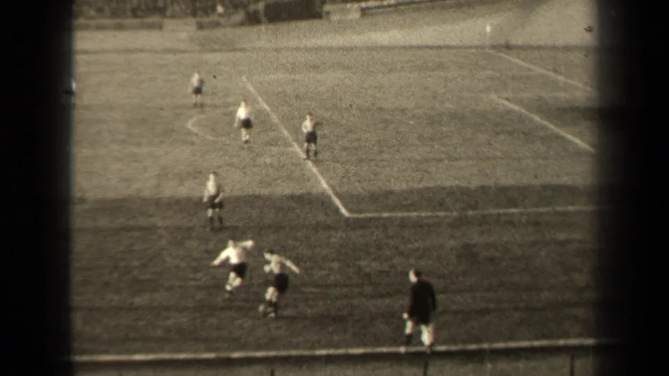 1947 Paris home-movie frame showing men's soccer play near the touchline, with field markings and spectators beyond.