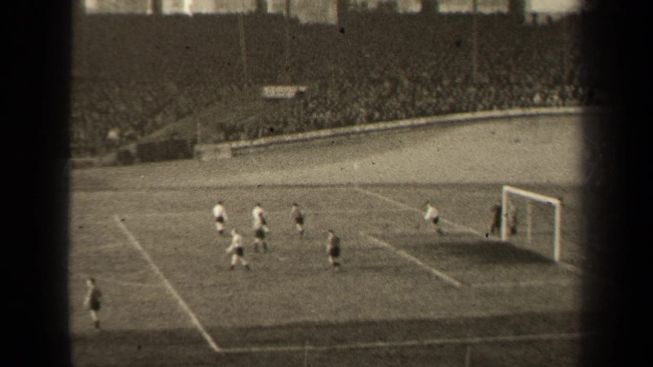 High-angle football match with players near a goal in a crowded stadium.