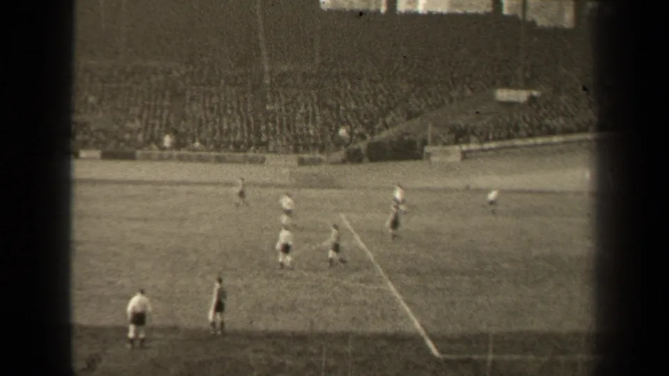 1947 Paris soccer match seen from a distant 8mm spectator angle, with players on the pitch and crowded stands in the background.