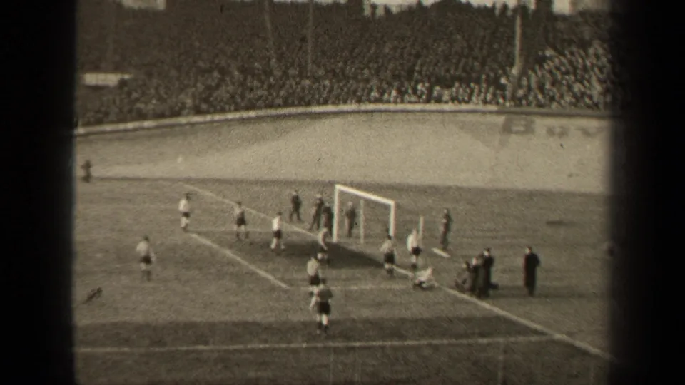 Paris football match footage from 1947 shows players moving around the penalty area before a crowded stadium stand.