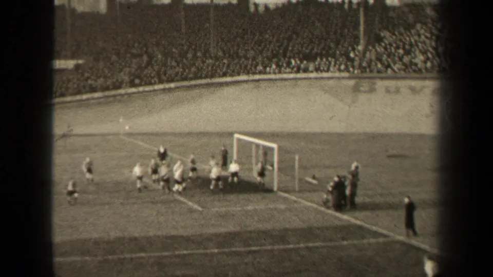1947 Paris 8mm frame showing soccer players gathered near the goal, with sideline figures and crowded stands in the background.