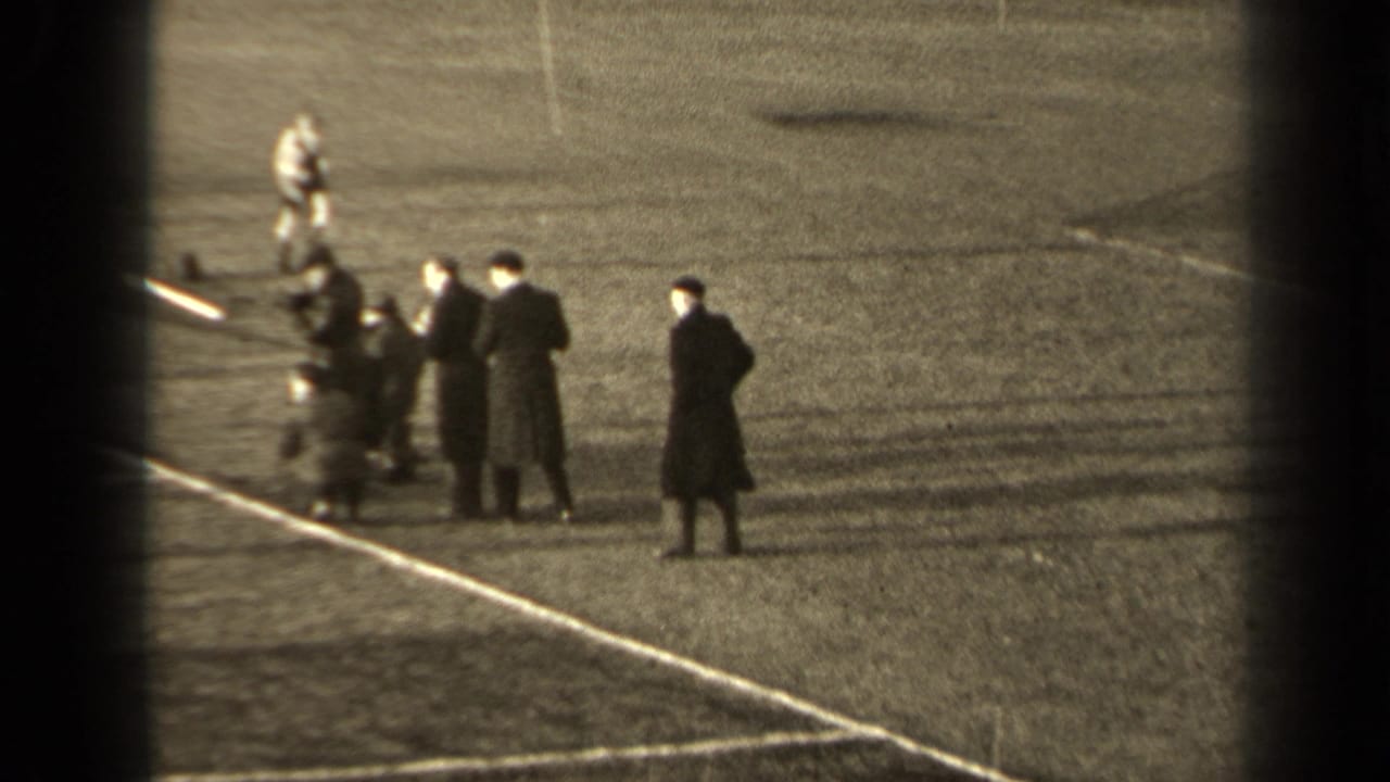 1947 Paris 8mm frame with players or sideline figures gathered near a marked football touchline, viewed from above and at a distance.