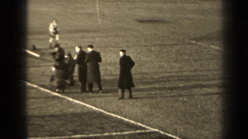 1947 Paris 8mm frame with players or sideline figures gathered near a marked football touchline, viewed from above and at a distance.