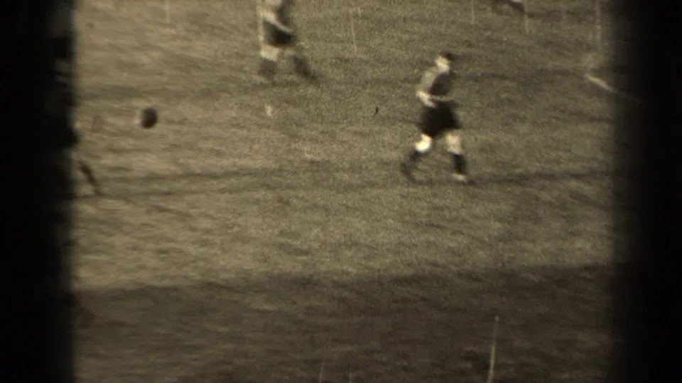 1947 Paris 8mm frame showing a football player running on a marked grass pitch, with other players blurred at the frame edges.
